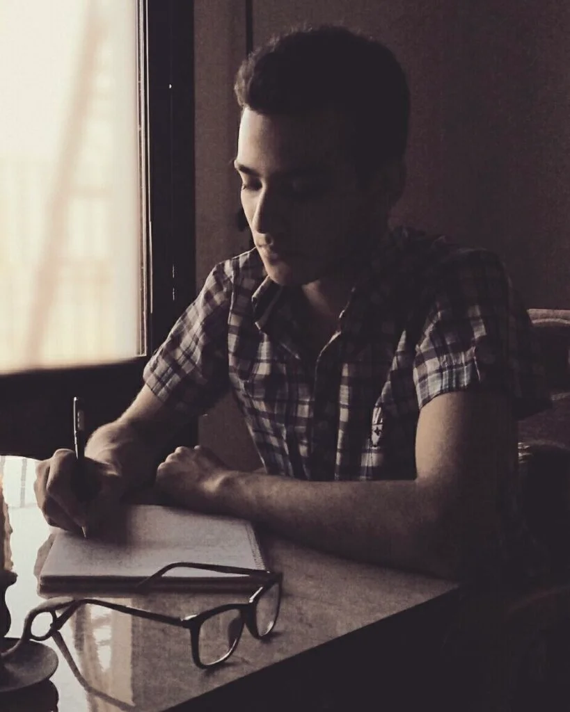 بشار قصاب في بداية رحلته مع الكتابة الإبداعية، يظهر وهو يكتب على دفتر